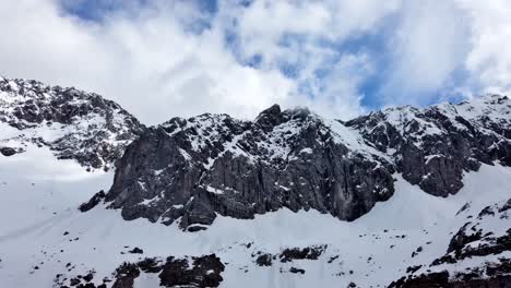 Zeitraffer-Kamera-Von-Links-Nach-Rechts-Schwenken-Von-Schneebedeckten-Bergen-Mit-Blauem-Himmel-Und-Wolken,-Die-über-Die-Berggipfel-Rollen