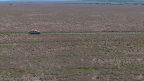 Drone-shot-of-off-road-vehicle-drives-through-grasslands-in-Serengeti