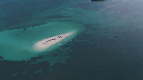Drone-shot-tropical-sand-island-full-of-people-and-boats