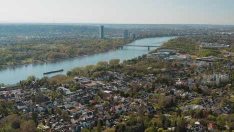 Drohnen-Luftpanoramaaufnahme-Bonn-Mit-Der-Konrad-Adenauer-Brücke,-Dem-Rhein-Mit-Einem-Schiff,-Dem-Kameha-Grand-Hotel-Und-Dem-Post-Tower-30p