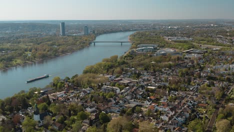 Drohnen-Panoramaaufnahme-Aus-Der-Luft-Von-Bonn-Mit-Der-Konrad-Adenauer-Brücke,-Dem-Rhein-Mit-Einem-Schiff,-Dem-Kameha-Grand-Hotel-Und-Dem-Post-Tower-25p