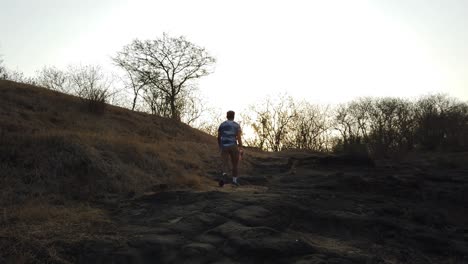 Man-Hikes-on-a-Nature-Trail-Outdoors-During-Sunset-in-a-Forest-and-Hilly-Terrain
