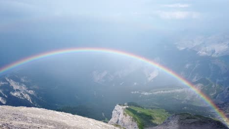 Slow-left-to-right-pan-over-alpine-gravel-field-in-german-alps-showing-a-double-rainbow-right-after-a-rainstorm