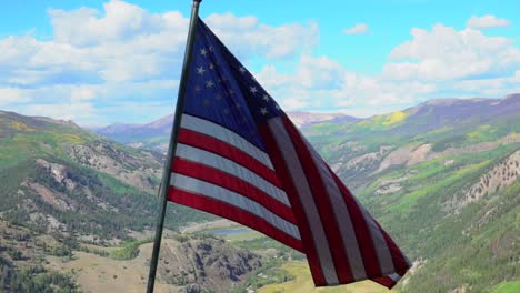 Bandera-Estadounidense-Ondeando-En-La-Cima-De-La-Montaña-Sobre-Un-Exuberante-Valle-Verde