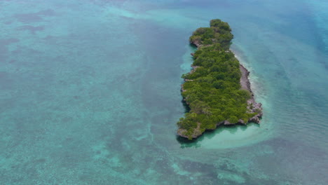 Circling-drone-shot-aroud-beautiful-tree-island-surrounded-by-turquoise-water