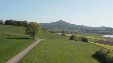 Drone---Aerial-panorama-shot-of-al-lonely-chapel-on-a-field-with-grass-and-a-road-with-panorama-of-the-seven-mountains---Siebengebirge-30p