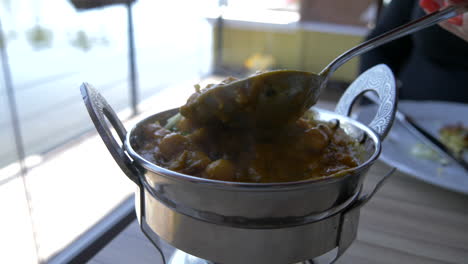 Lifting-a-spoon-out-of-hot-indian-food-or-curry-dishes-with-steam