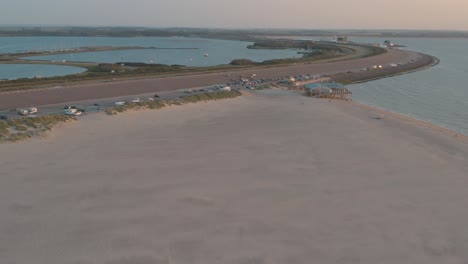 Cinematic-drone---aerial-panorama-shot-of-the-green-and-sandy-nature-beach-at-sunset-with-tourists-at-Zeeland-at-the-north-sea,-Netherlands,-30p