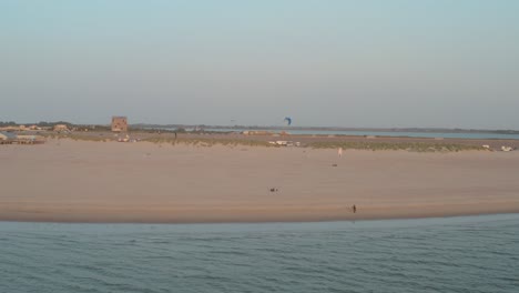 Cinematic-drone---aerial-panorama-circling-shot-of-the-green-and-sandy-nature-beach-at-sunset-with-tourists-and-people-with-Buggykiting-at-Zeeland-at-the-north-sea,-Netherlands,-30p