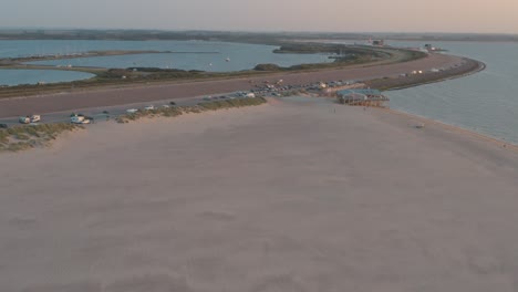 Cinematic-drone---aerial-panorama-shot-of-the-green-and-sandy-nature-beach-at-sunset-with-tourists-at-Zeeland-at-the-north-sea,-Netherlands,-25p