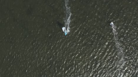 Drone---Aerial-top-shot-of-surfer-on-a-blue,-wavy-and-windy-sea-on-a-sunny-day,-25p