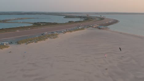 Cinematic-drone---aerial-shot-of-the-green-and-sandy-nature-beach-at-sunset-with-tourists-and-people-with-Buggykiting-at-Zeeland-at-the-north-sea,-Netherlands,-30p
