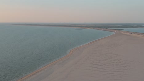 Filmische-Drone---Luftpanoramaaufnahme-Des-Sandigen-Naturstrandes-Bei-Sonnenuntergang-Mit-Touristen-Und-Menschen-Beim-Buggykiten-In-Zeeland-An-Der-Nordsee,-Niederlande,-30p