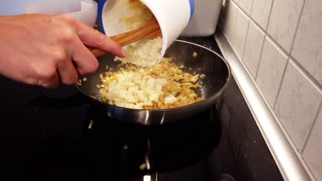 Adding-processed-cauliflower-to-a-frying-pan-with-onions-already-cooking-in-it