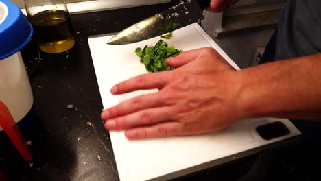Chopping-fresh-coriander-on-a-white-cutting-board-with-a-large-knife