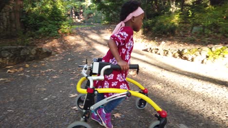 Schwarzes-Mädchen-Mit-Zerebraler-Lähmung,-Das-Mit-Ihrem-Hilfsgerät-Im-Park-Spazieren-Geht