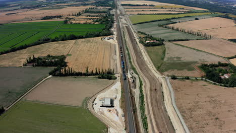 Aerial-overhead-of-a-train-in-France-as-it-travels-by-construction-site-then-into-the-distance