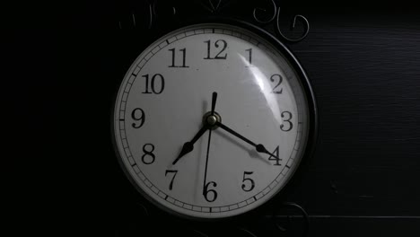 Time-lapse-of-a-small-black-clock-in-a-dimly-lit-room