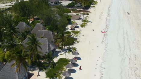 Flying-above-luxury-bungalows-on-exotic-Zanzibar-island,-along-turquoise-blue-ocean-coast