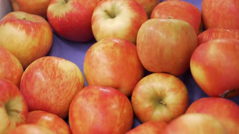 Hermosas-Manzanas-Rojas-Maduras-En-El-Supermercado-Siendo-Agarradas-Por-Una-Mano