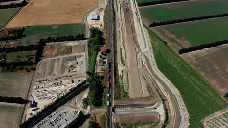 Aerial-overhead-of-a-train-in-France-as-it-travels-by-construction-site-then-into-the-distance