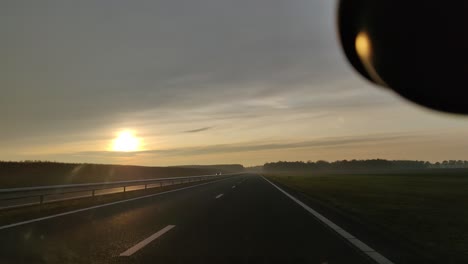 Mirando-Por-El-Parabrisas-Del-Coche-Conduciendo-Por-La-Autopista-N33-Durante-La-Puesta-De-Sol-En-Drenthe,-Países-Bajos