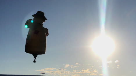 Scarecrow-hot-air-balloon-liftoff,-silhouetted-by-sun