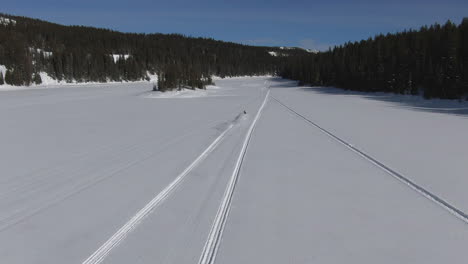 drone-follows-two-snowmobiles-across-a-frozen-lake-in-colorado