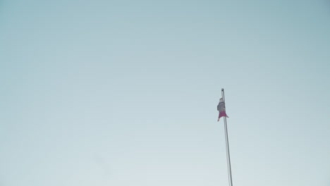 A-flag-windsock-waves-in-the-breeze-on-a-flagpole-against-a-clear-blue-sky-still-shot