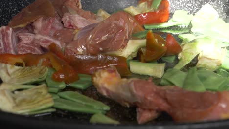 Frisches-Fleisch-Und-Gemüse,-Das-In-Zeitlupe-In-Einem-Paella-Gericht-Gekocht-Wird