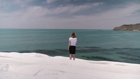 Woman-standing-on-white-cliff-Scala-dei-Turchi-by-sea-coastline-in-Sicily