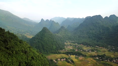 Luftaufnahme-Von-üppigen-Grünen-Bewaldeten-Hügeln-In-Vietnam-Mit-Lokalen-Dörfern-Im-Talboden-Darunter