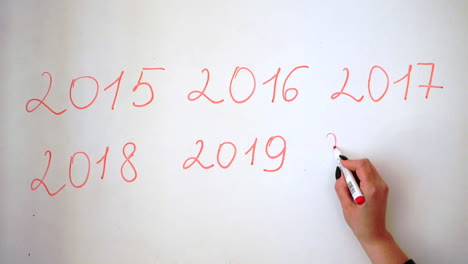 Writing-the-actual-year,-date-behind-the-last-year's-dates-on-a-whiteboard-with-red-marker,-2020