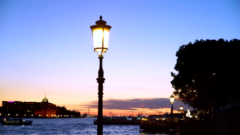 Daueraufnahme-Einer-Beleuchteten-Laternensäule-In-Venedig-Vor-Den-Kanälen-Bei-Sonnenuntergang