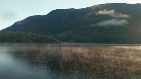 Aerial-of-Foggy-Mountain-Lake-at-Sunrise-Flying-Forward-Above-Water