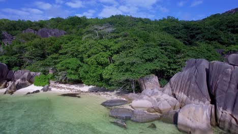 Beach-with-granite-rocks,-white-sand,-and-blue-sky-in-tropical-Paradise,-La-Digue,-Seychelles---drone-shot
