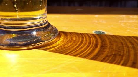 Glass-of-carbonated-beer-casting-shadow-on-wooden-table