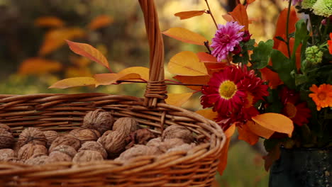 Wicker-basket-with-walnuts-next-to-vase-of-flowers-outside-on-table