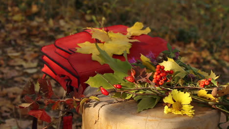 Herbstliche-Gartenszene-Mit-Roter-Tasche,-Die-Zusammen-Mit-Blättern-Und-Beerenzweig-Auf-Einer-Bank-Ruht