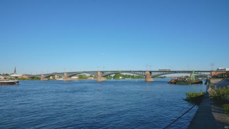 Panorama-shot-of-the-Theodor-Heuss-Brücke-bridge-between-the-cities-mainz-and-wiesbaden,-Hesse-and-rhineland-palatinate-with-the-river-rhine-and-a-cargo-ship-on-a-sunny-summer-day
