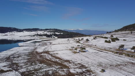Drohnenaufnahme-Eines-Verschneiten-Fußwegs,-Umgeben-Von-Pinien-In-Der-Nähe-Des-Sees-Im-Winter