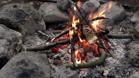 Small-Campfire-surrounded-by-rocks-peacefully-burning-with-orange-flames