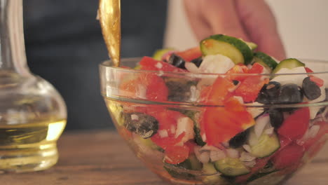 Feta-Salat-Wird-Mit-Einem-Löffel-Auf-Dem-Tisch-Neben-Einer-Flasche-Olivenöl-Gemischt