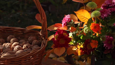 Large-wicker-basket-with-walnuts-next-to-bouquet-of-flowers-outside-on-table