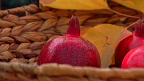 Close-up-of-ripe-red-pomegranates-in-wicker-basket-on-table-in-garden