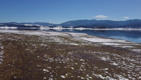 Drone-Vuela-Sobre-Un-Lago-Con-Un-Reflejo-De-Una-Montaña-Y-Cielo-En-Invierno