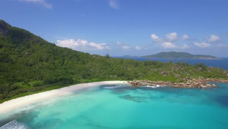 Breiter-Drohnenschuss-Mit-Blick-Auf-Den-Leeren-Und-Einsamen-Tropischen-Strand-Im-Paradies-Auf-La-Digue,-Seychellen,-Mit-Blauem-Himmel,-Weißem-Sand-Und-Türkisfarbenem-Wasser