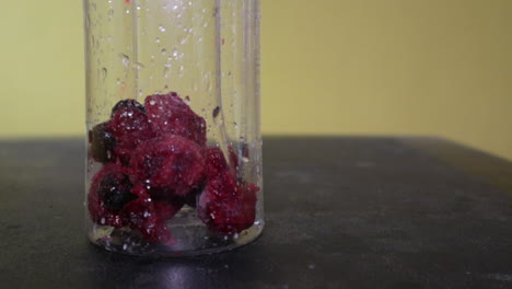Mixed-Frozen-Berries-Dropped-Inside-The-Wet-Transparent-Glass-Container--Eye-Level-Shot