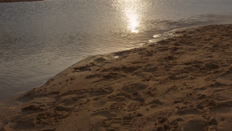 Neigung-Von-Fußspuren-Im-Sand-Bis-Zum-Sonnenuntergang-über-Dem-Wasser