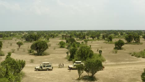 Safari-jeeps-parked-in-the-middle-of-Ugandan-nature-reserve-with-spare-trees-and-sand